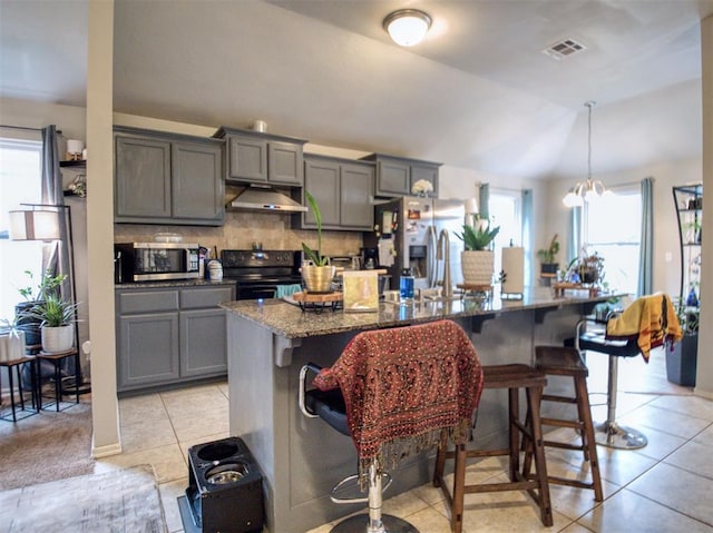 12825 William Penn Blvd, Oklahoma City, OK 73120 - kitchen featuring appliances with stainless steel finishes, gray cabinetry, under cabinet range hood, a kitchen breakfast bar, and healthy amount of natural light