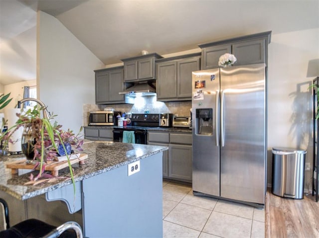 12825 William Penn Blvd, Oklahoma City, OK 73120 - kitchen featuring stainless steel appliances, under cabinet range hood, lofted ceiling, backsplash, and dark stone counters