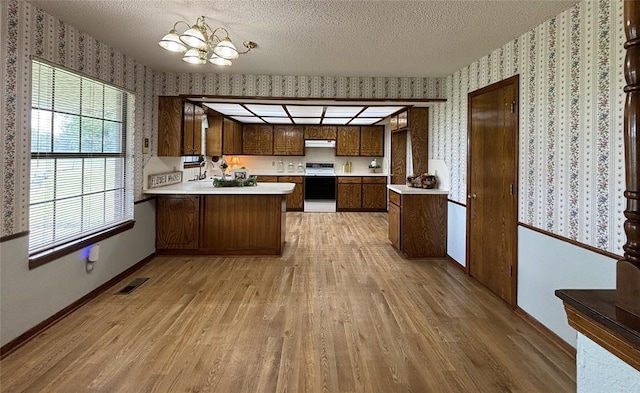 425 W Crooked Branch Way, Mustang, OK 73064 - kitchen featuring wallpapered walls, light wood-type flooring, stove, light countertops, and a chandelier