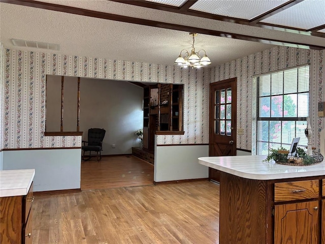 425 W Crooked Branch Way, Mustang, OK 73064 - kitchen featuring wallpapered walls, light countertops, light wood-type flooring, a chandelier, and wainscoting