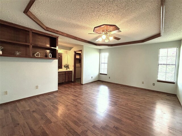 425 W Crooked Branch Way, Mustang, OK 73064 - unfurnished living room featuring a textured ceiling, a ceiling fan, dark wood finished floors, and a raised ceiling