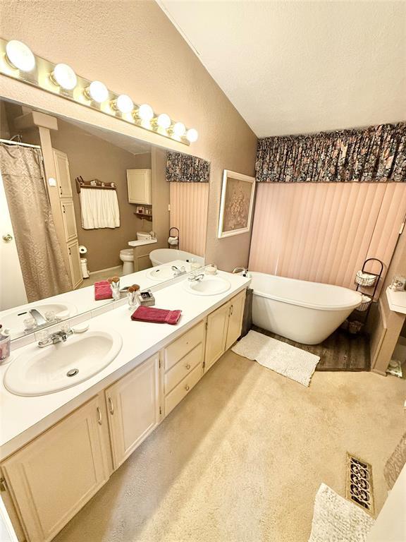 305 N Greer Ave, Duke, OK 73532 - bathroom with lofted ceiling, double vanity, a soaking tub, toilet, and a shower with curtain
