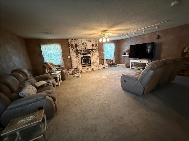 carpeted living area with ceiling fan, healthy amount of natural light, a textured ceiling, and a brick fireplace
