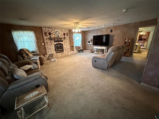 carpeted living area featuring a ceiling fan, a fireplace, a textured ceiling, and rail lighting