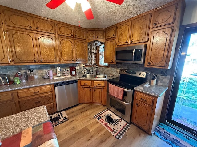 kitchen featuring stainless steel appliances, a sink, brown cabinets, and a textured ceiling
