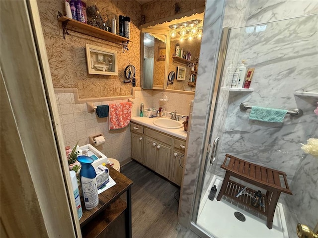 full bathroom featuring vanity, a shower stall, wood finished floors, tile walls, and wainscoting