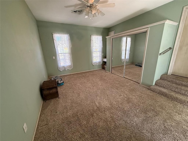 unfurnished bedroom featuring carpet floors, a closet, ceiling fan, and baseboards