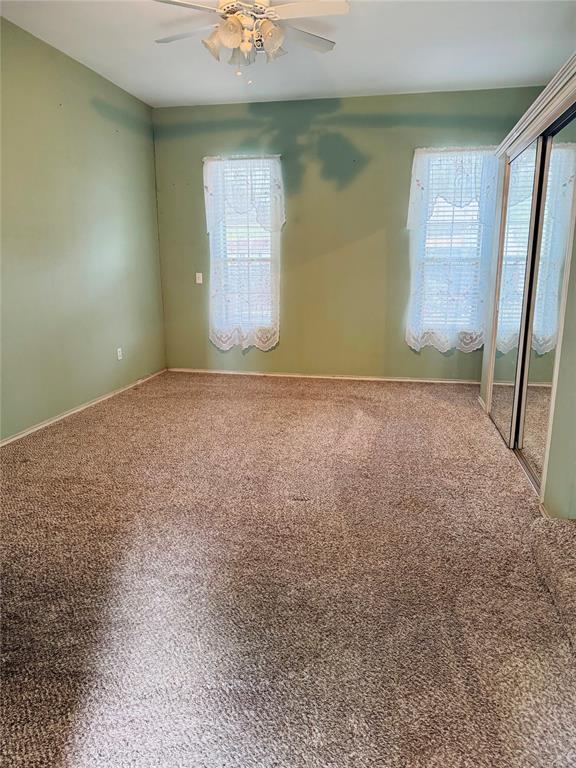 empty room featuring ceiling fan, carpet floors, and baseboards