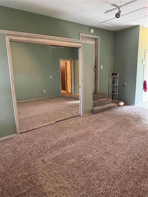 spare room featuring carpet floors, stairs, and baseboards