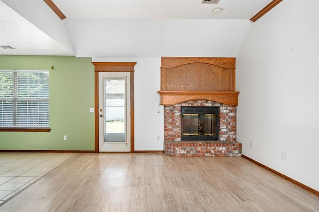 11014 Madison Ave, Midwest City, OK 73130 - unfurnished living room with wood finished floors, vaulted ceiling, a brick fireplace, and baseboards