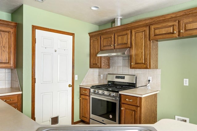 11014 Madison Ave, Midwest City, OK 73130 - kitchen featuring under cabinet range hood, stainless steel range with gas stovetop, brown cabinetry, backsplash, and recessed lighting