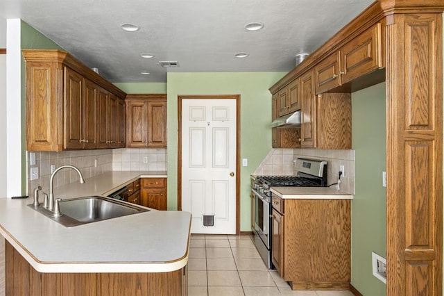 11014 Madison Ave, Midwest City, OK 73130 - kitchen featuring gas stove, a sink, under cabinet range hood, a peninsula, and backsplash