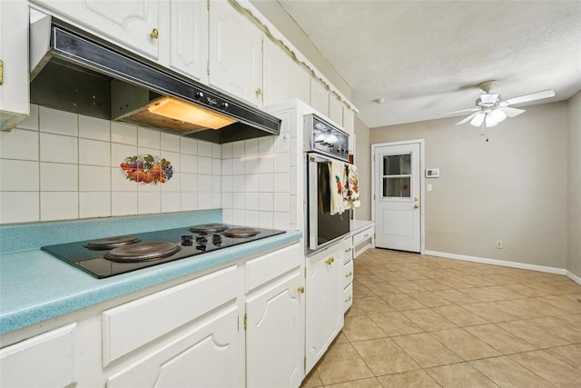 1313 SW 69th St, Oklahoma City, OK 73159 - kitchen featuring under cabinet range hood, oven, black electric cooktop, tasteful backsplash, and white cabinetry