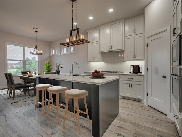 7217 NW 154th St, Edmond, OK 73013 - kitchen featuring a sink, a chandelier, a center island with sink, light countertops, and tasteful backsplash