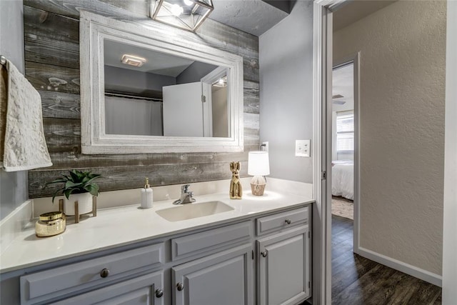 2416 Northwood Ln, Edmond, OK 73013 - ensuite bathroom with vanity, wood finished floors, a textured wall, and baseboards