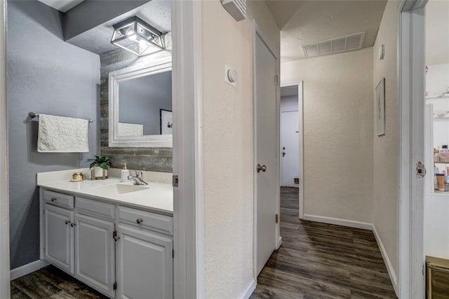 2416 Northwood Ln, Edmond, OK 73013 - bathroom featuring vanity, wood finished floors, baseboards, and a textured wall
