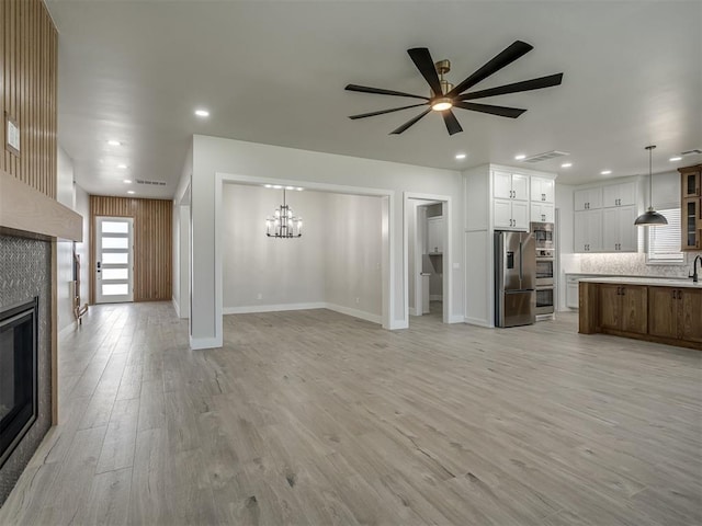 6305 NW 153rd St, Edmond, OK 73013 - unfurnished living room with a fireplace, a ceiling fan, a chandelier, light wood-style floors, and recessed lighting