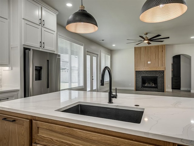 6305 NW 153rd St, Edmond, OK 73013 - kitchen featuring stainless steel fridge, light stone counters, a ceiling fan, pendant lighting, and a large fireplace