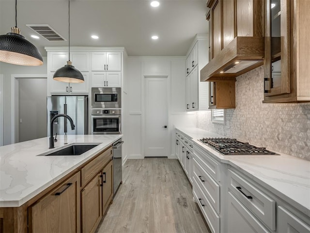 6305 NW 153rd St, Edmond, OK 73013 - kitchen featuring wall chimney exhaust hood, stainless steel appliances, light wood-style flooring, backsplash, and light stone counters