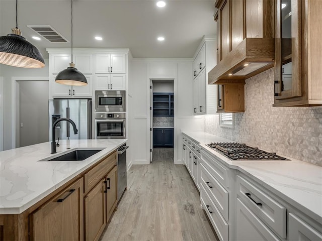 6305 NW 153rd St, Edmond, OK 73013 - kitchen with wall chimney range hood, stainless steel appliances, light wood-type flooring, tasteful backsplash, and light stone counters
