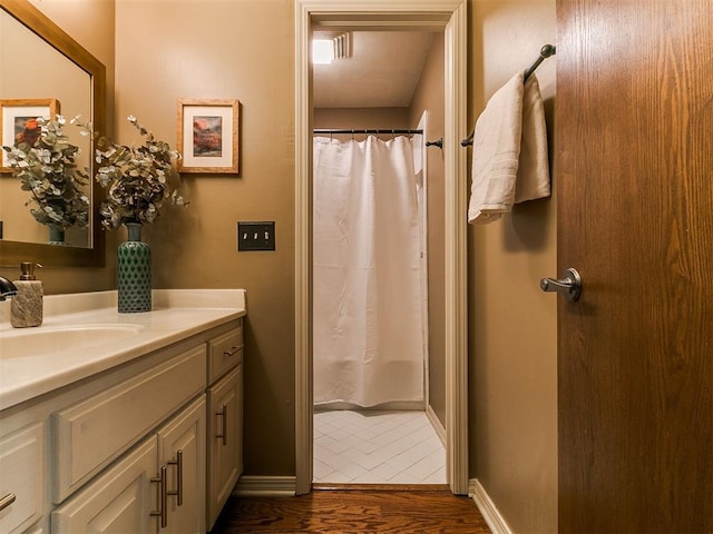 601 Holly Dr, Edmond, OK 73034 - bathroom with vanity, wood finished floors, baseboards, and a shower with curtain