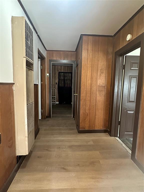 408 Wake St, Broken Bow, OK 74728 - hallway with light wood-style floors, wood walls, and a heating unit