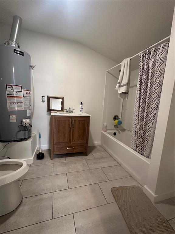 408 Wake St, Broken Bow, OK 74728 - full bathroom featuring gas water heater, shower / bathtub combination with curtain, toilet, tile patterned floors, and baseboards