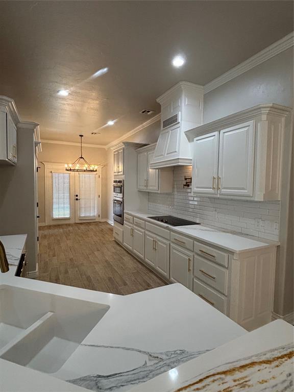 2921 Summit Crossing Pkwy, Norman, OK 73071 - kitchen with a chandelier, black electric cooktop, ornamental molding, light countertops, and wood finished floors
