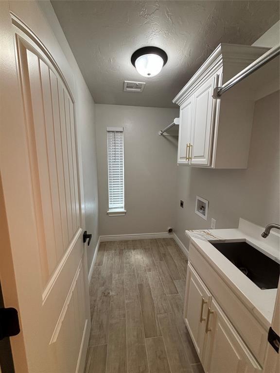2921 Summit Crossing Pkwy, Norman, OK 73071 - laundry area with electric dryer hookup, wood finished floors, cabinet space, hookup for a washing machine, and baseboards