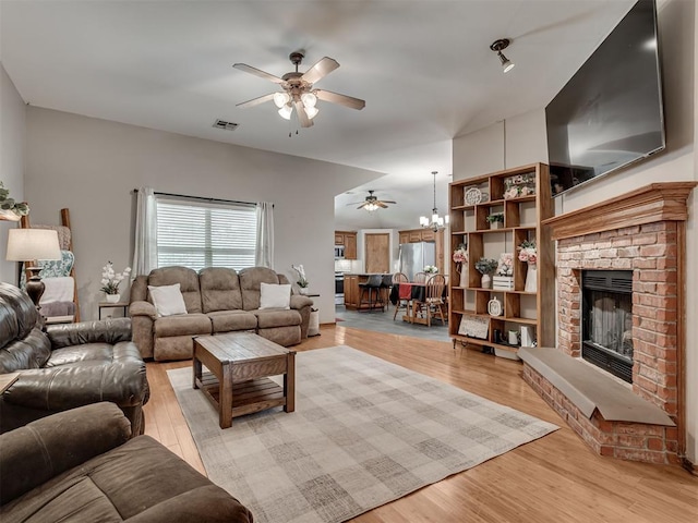 2120 NE 4th St, Moore, OK 73160 - living room featuring ceiling fan, a fireplace, light wood-type flooring, and a chandelier