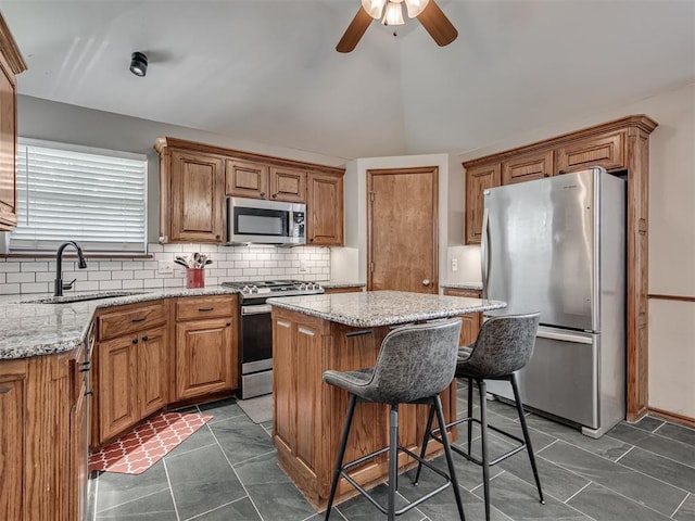2120 NE 4th St, Moore, OK 73160 - kitchen featuring stainless steel appliances, a sink, a kitchen island, tasteful backsplash, and ceiling fan