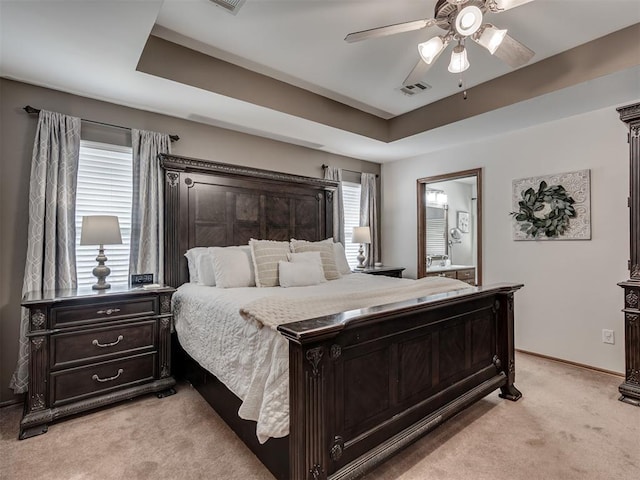 2120 NE 4th St, Moore, OK 73160 - bedroom featuring light colored carpet, a raised ceiling, a ceiling fan, connected bathroom, and baseboards