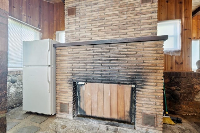 624 N Wentz St, Guthrie, OK 73044 - detailed view of freestanding refrigerator, a brick fireplace, and wooden walls