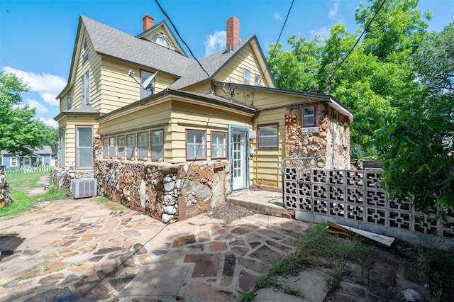 624 N Wentz St, Guthrie, OK 73044 - back of property featuring a patio area, stone siding, a chimney, and cooling unit