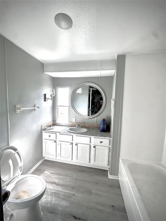 101869 S 3570th Rd, Prague, OK 74864 - full bathroom with vanity, a bathtub, wood finished floors, a textured ceiling, and baseboards