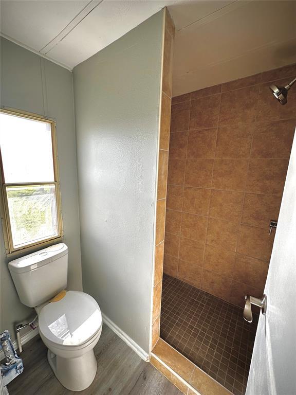 101869 S 3570th Rd, Prague, OK 74864 - bathroom with a shower stall, toilet, wood finished floors, and baseboards
