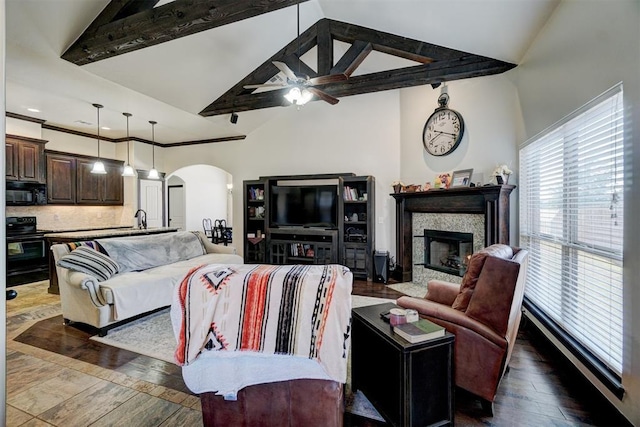 19009 Meadows Crossing Dr, Edmond, OK 73012 - living room featuring arched walkways, high vaulted ceiling, ceiling fan, a glass covered fireplace, and dark wood-style floors