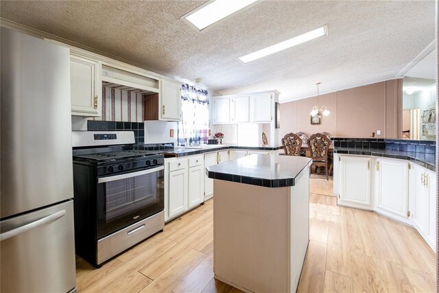 1020 S Walnut Ave, Erick, OK 73645 - kitchen with appliances with stainless steel finishes, a textured ceiling, dark countertops, a peninsula, and white cabinetry