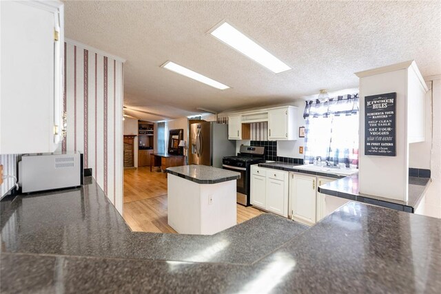 1020 S Walnut Ave, Erick, OK 73645 - kitchen featuring appliances with stainless steel finishes, a textured ceiling, white cabinets, a peninsula, and a sink