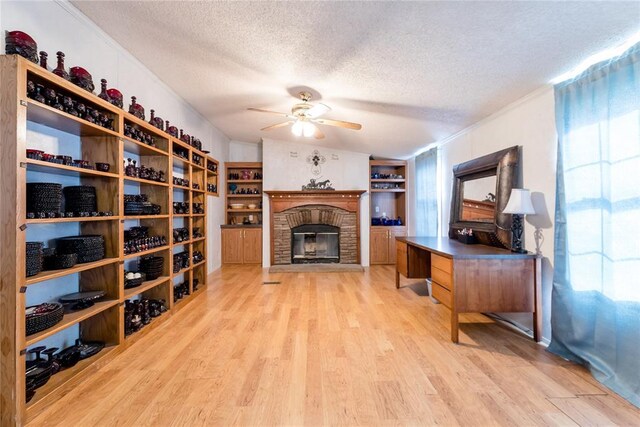 1020 S Walnut Ave, Erick, OK 73645 - wine area featuring a textured ceiling, ceiling fan, light wood-style flooring, and a fireplace