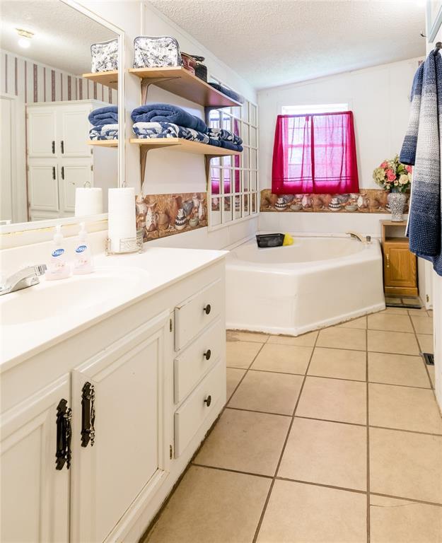 1020 S Walnut Ave, Erick, OK 73645 - bathroom featuring vanity, a bath, tile patterned floors, and a textured ceiling