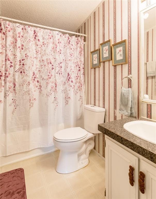 1020 S Walnut Ave, Erick, OK 73645 - bathroom featuring toilet, vanity, tile patterned floors, a textured ceiling, and wallpapered walls