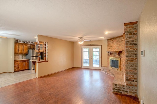 5821 NW 89th St, Oklahoma City, OK 73132 - unfurnished living room with ceiling fan, baseboards, light wood-style floors, a fireplace, and a textured ceiling