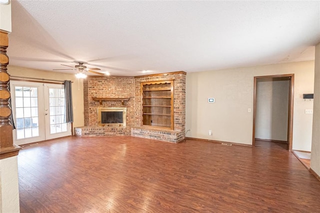 5821 NW 89th St, Oklahoma City, OK 73132 - unfurnished living room with built in features, wood finished floors, ceiling fan, a fireplace, and a textured ceiling