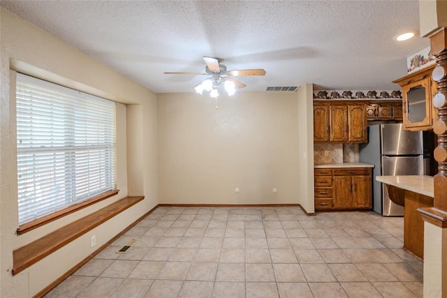5821 NW 89th St, Oklahoma City, OK 73132 - kitchen featuring freestanding refrigerator, a ceiling fan, light countertops, brown cabinets, and backsplash