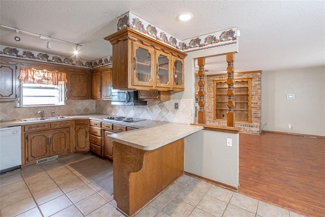 5821 NW 89th St, Oklahoma City, OK 73132 - kitchen with white dishwasher, a peninsula, a textured ceiling, a sink, and rail lighting