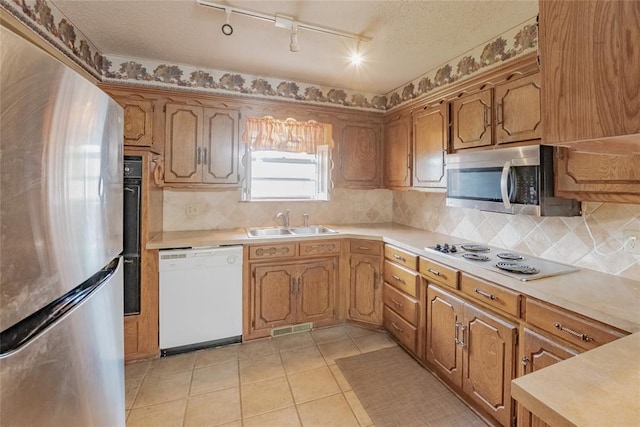 5821 NW 89th St, Oklahoma City, OK 73132 - kitchen with stainless steel appliances, a sink, track lighting, light countertops, and backsplash