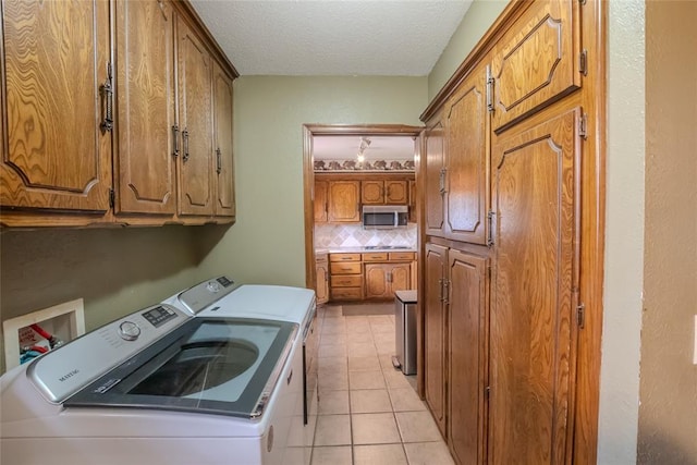 5821 NW 89th St, Oklahoma City, OK 73132 - washroom with washing machine and dryer, a textured ceiling, cabinet space, and light tile patterned flooring