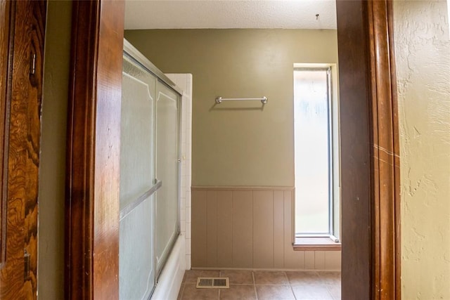 5821 NW 89th St, Oklahoma City, OK 73132 - bathroom with tile patterned floors, wainscoting, and bath / shower combo with glass door