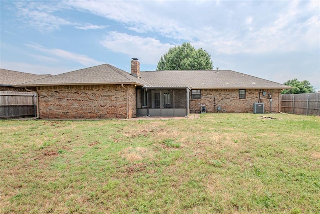5821 NW 89th St, Oklahoma City, OK 73132 - rear view of house featuring a sunroom, a chimney, brick siding, central AC unit, and roof with shingles